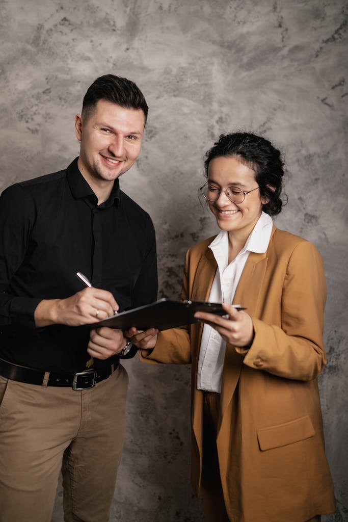 Two professionals finalize a real estate contract with a clipboard and pen.